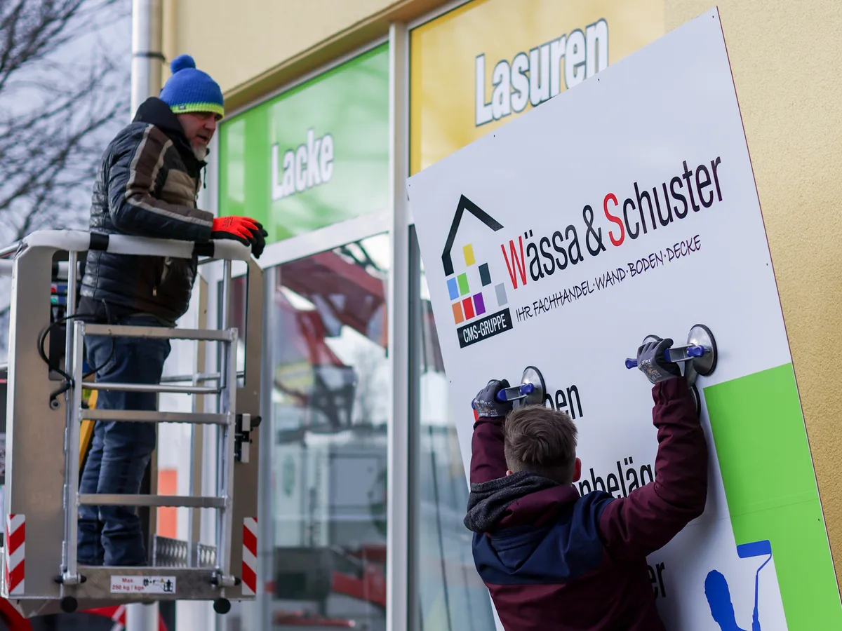 Fauss-Team montiert ein Werbeschild beim Kunden